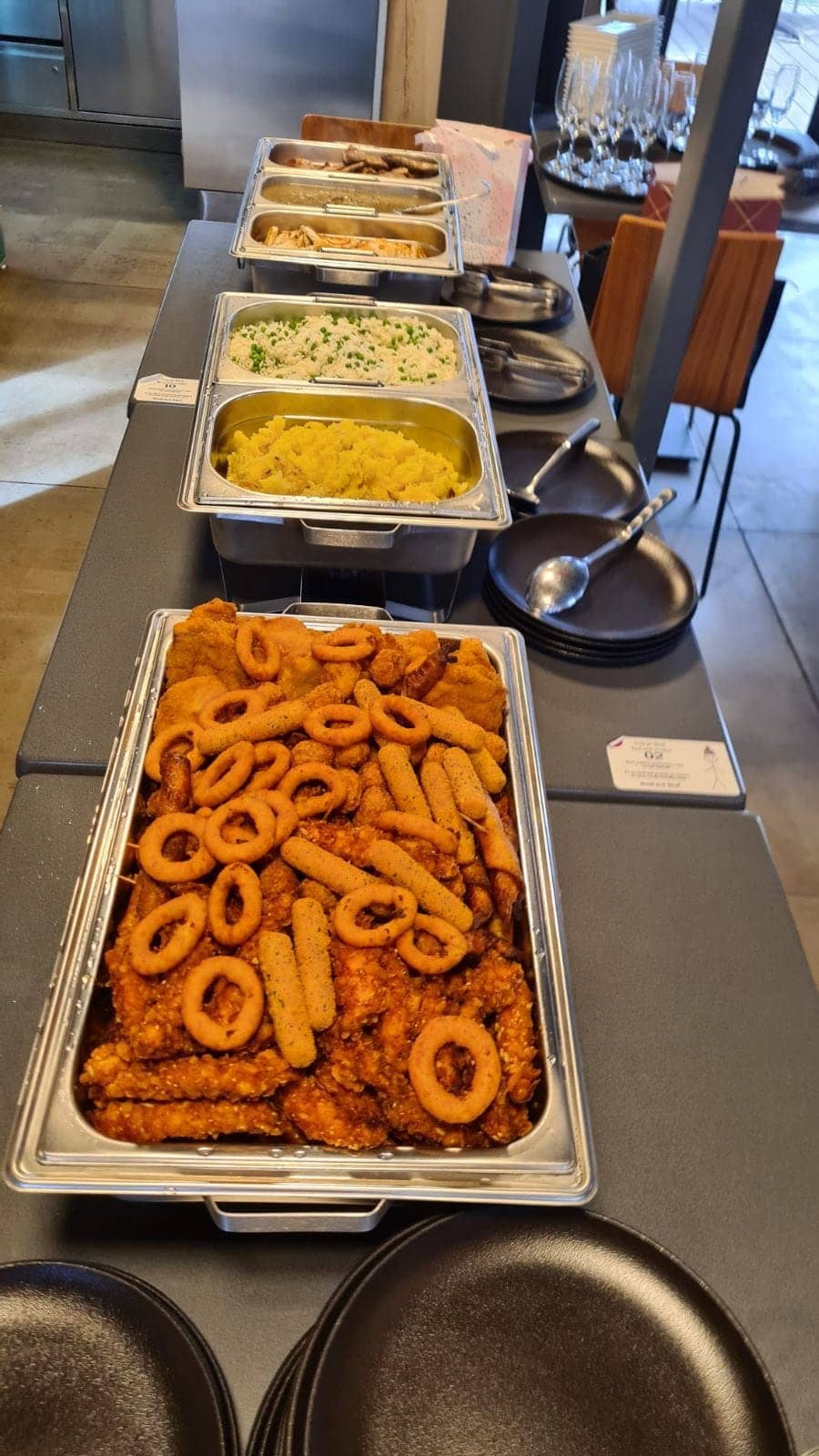 A buffet of trays: fried calamari and onion rings, rice, potatoes
