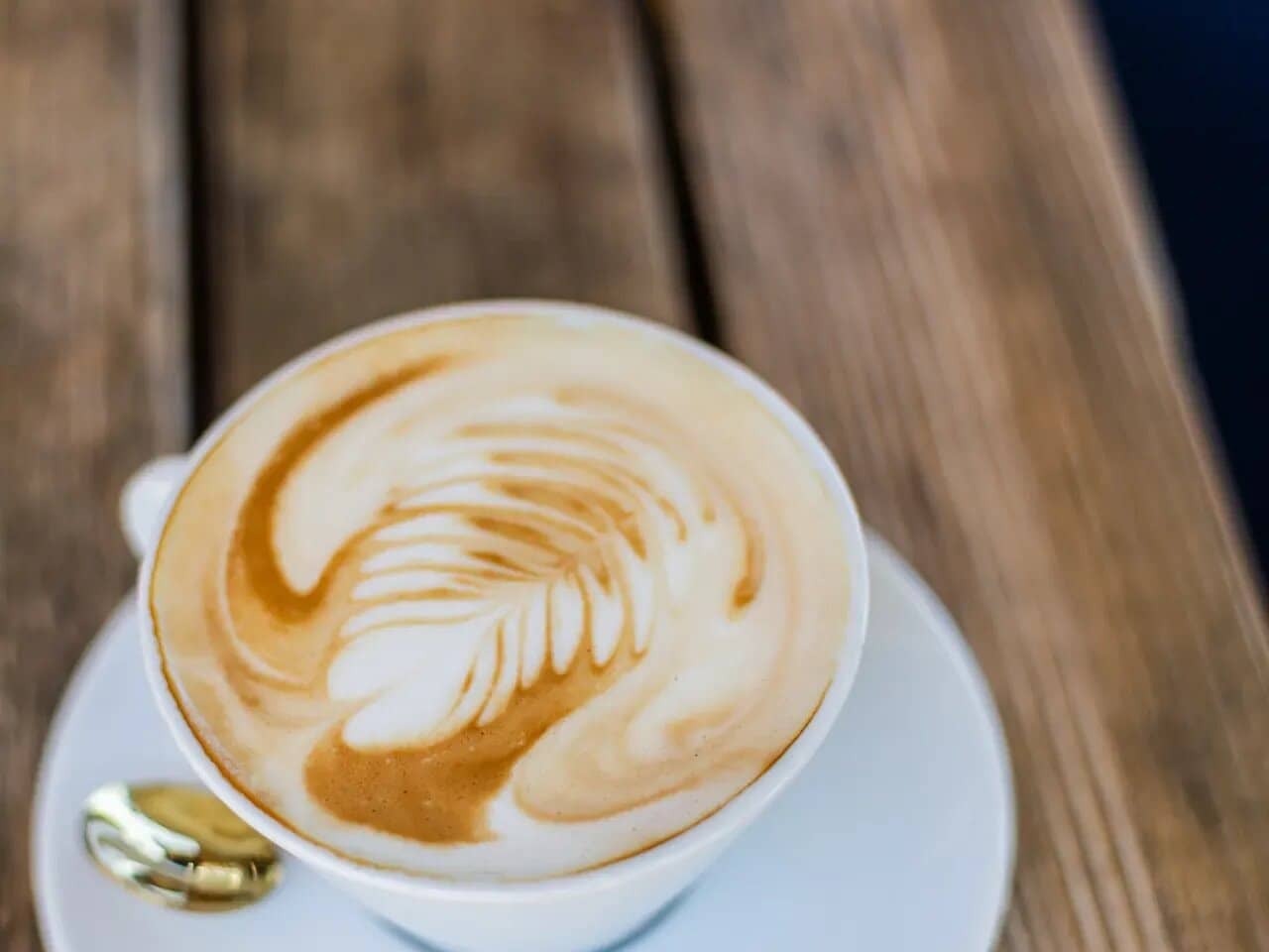 A cappuccino with latte art on a wooden table